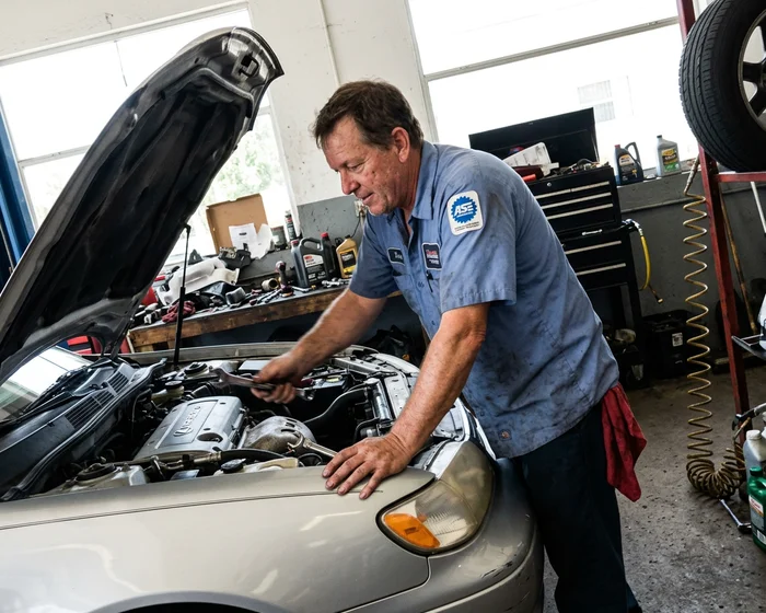 ASE-certified mechanic working under the hood of a customer vehicle at Pinto's Auto Repair in Naples