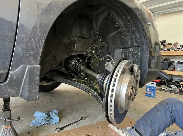 Torn CV axle boot with grease thrown inside the wheel well